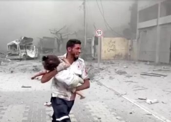 Paramedis berlari membawa seorang anak yang terluka saat Israel menghancurkan gedung di Gaza. Foto: Reuters.